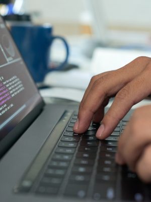 Hands of programmer writing code on laptop